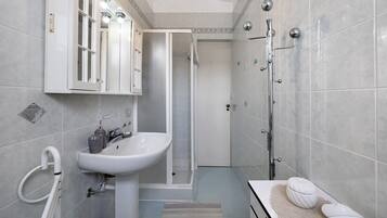 Une salle de bain moderne équipée d’un lavabo, d’un miroir, d’une douche et de toilettes.