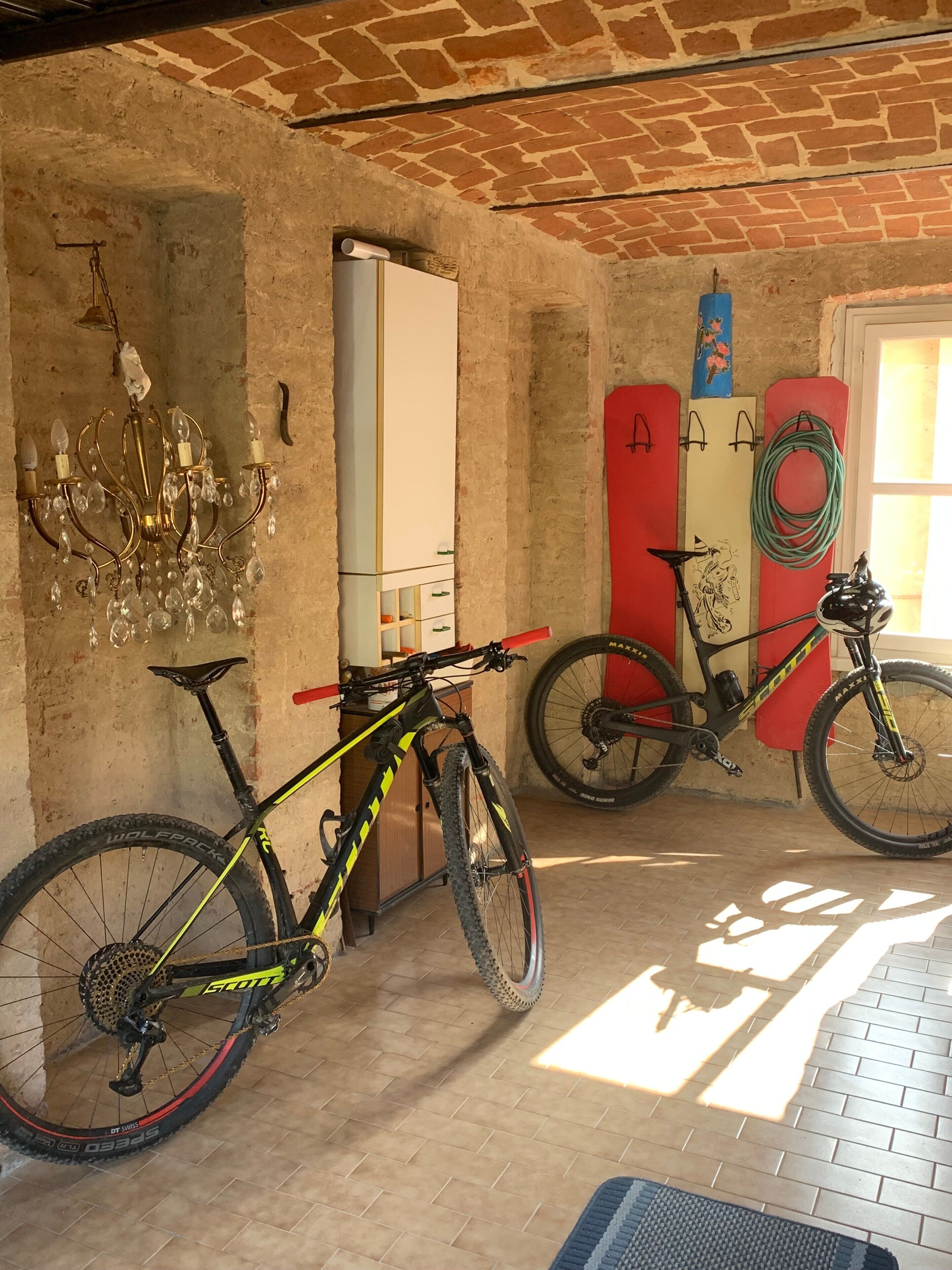 Ein Zimmer mit Backsteinwand, einer Kristallleuchter, einem Fahrrad und einem Surfbrett.