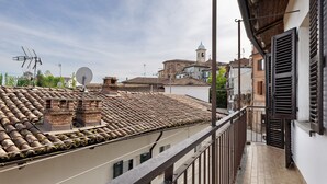 A rooftop terrace with a tiled roof, satellite dishes, and a traditional building with a bell tower in the background. - Holiday Home 'Dello Zio Birba' with Balcony and Wi-Fi (Portacomaro)