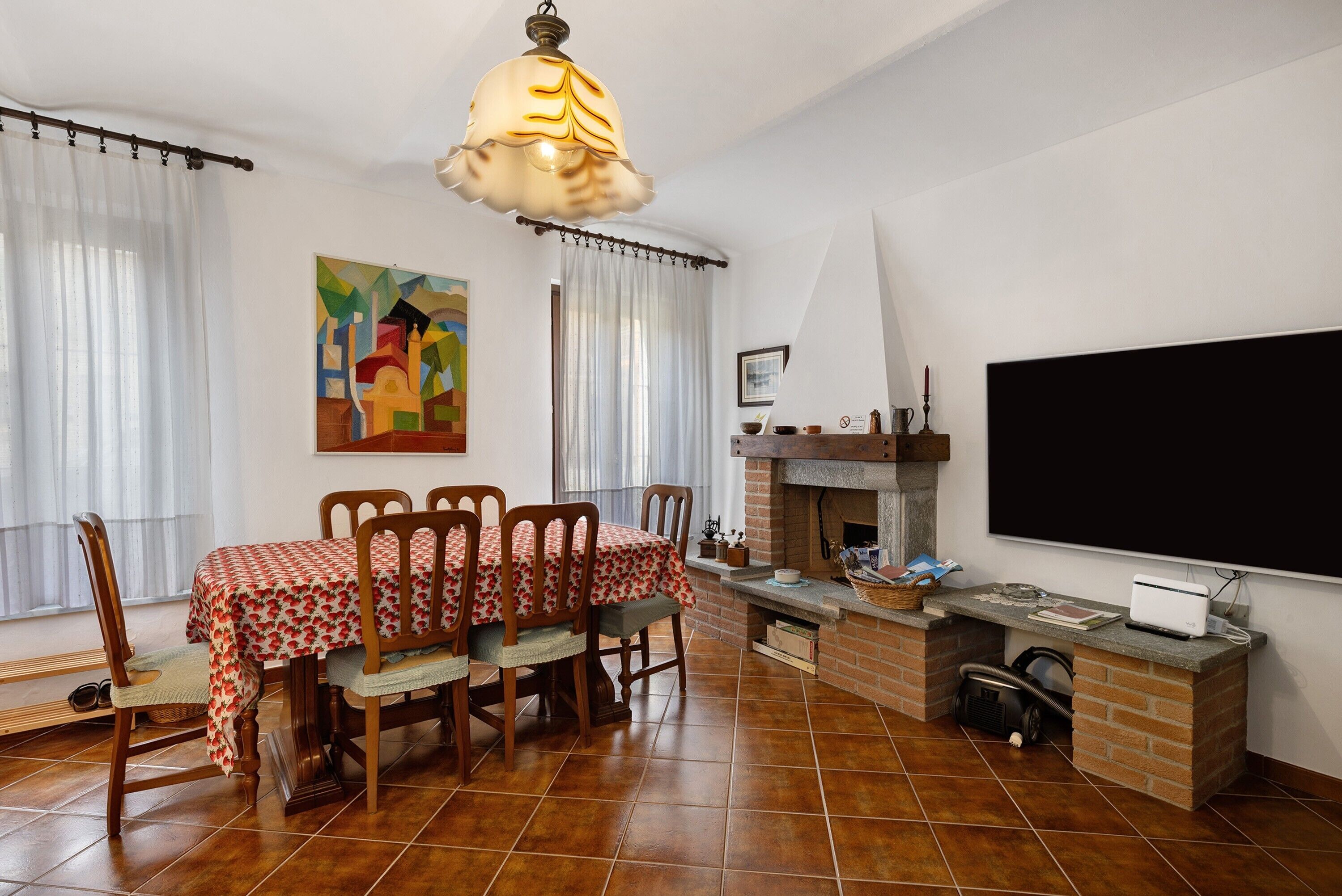 Un comedor con una mesa dispuesta para cuatro, una chimenea, un televisor y un cuadro en la pared.