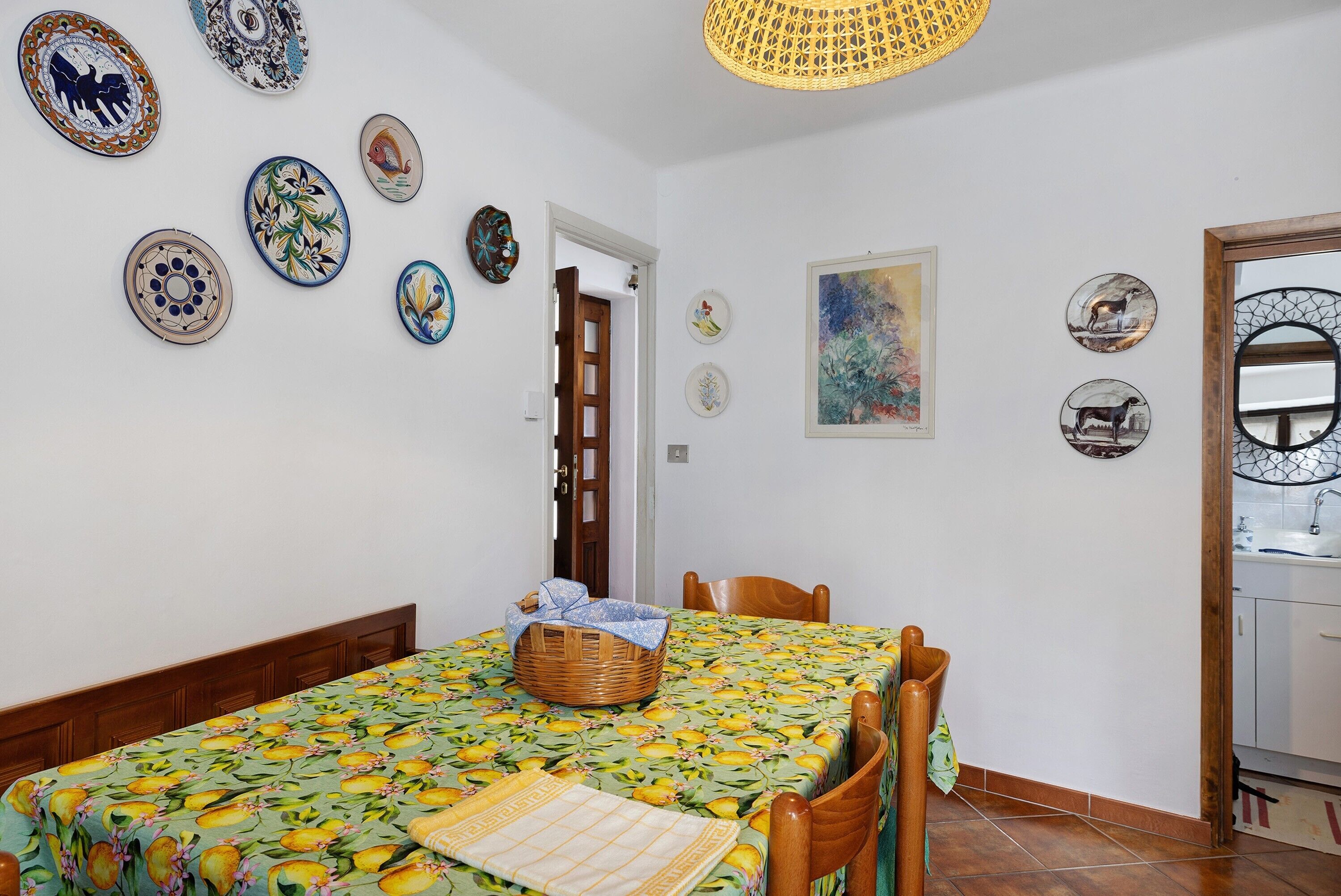 A dining area with a table set for four, a wicker basket on the table, and a door leading to another room.