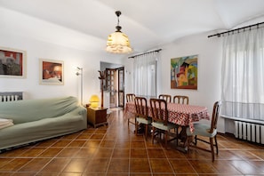 A dining area with a table set for four, a sofa, and a lamp.