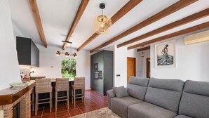 A modern kitchen with a dining area, a grey sofa, and a fireplace.