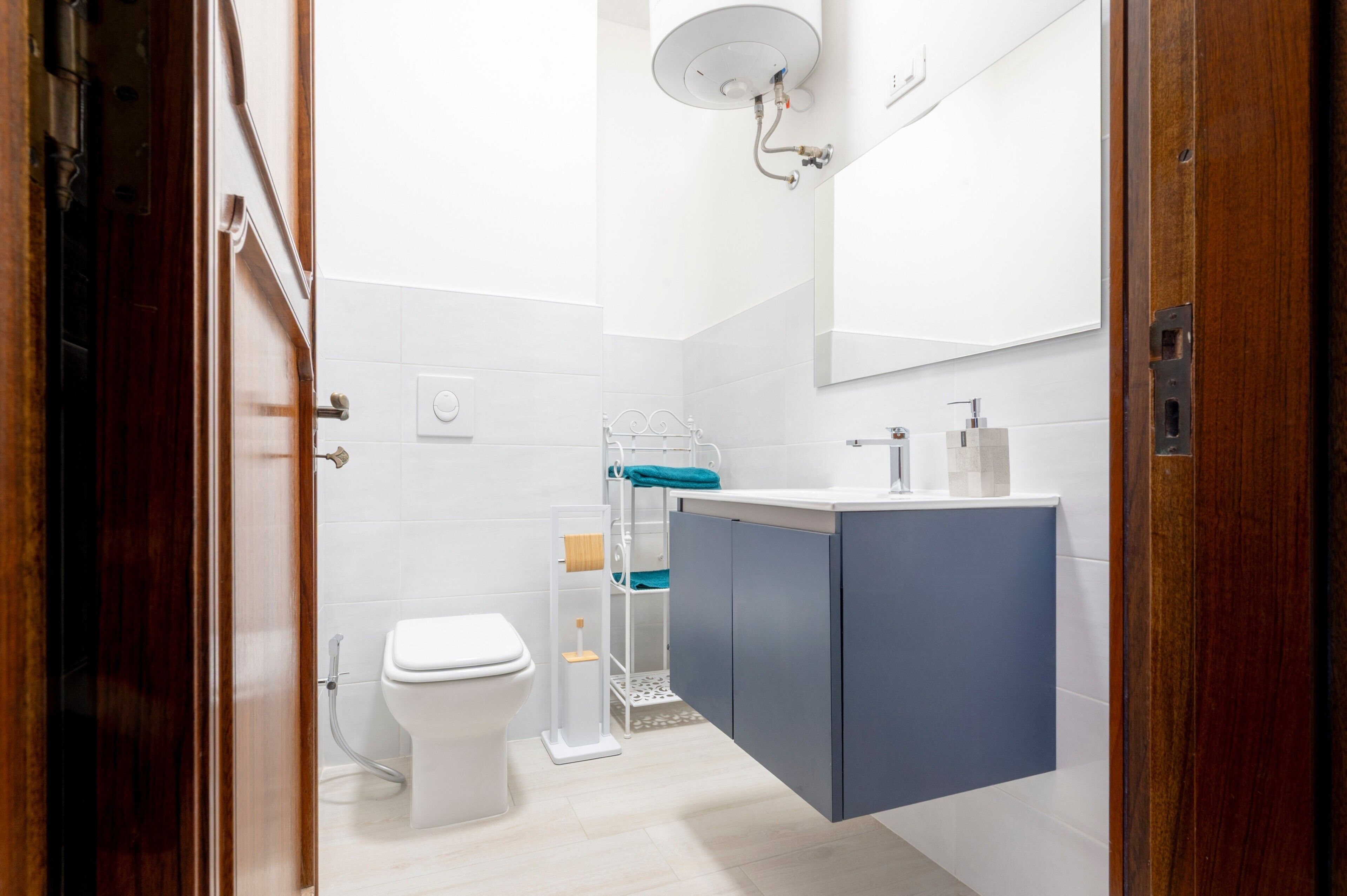 Un baño moderno con inodoro blanco, tocador azul y lavamanos blanco.