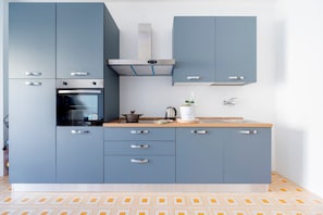 Een moderne keuken met grijze kastjes, een ingebouwde oven en een roestvrijstalen afzuigkap.