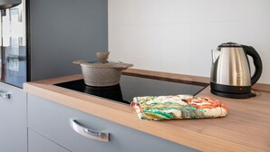 A modern kitchen with a stove, a kettle, and a patterned cloth on the counter. - Apartment 'Stella' with Sea View, Wi-Fi and Air Conditioning (Otranto)