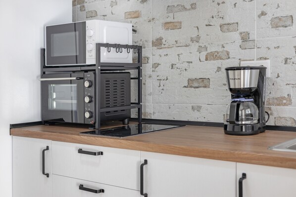 A kitchen with a coffee maker, a microwave, and a toaster on a rack.