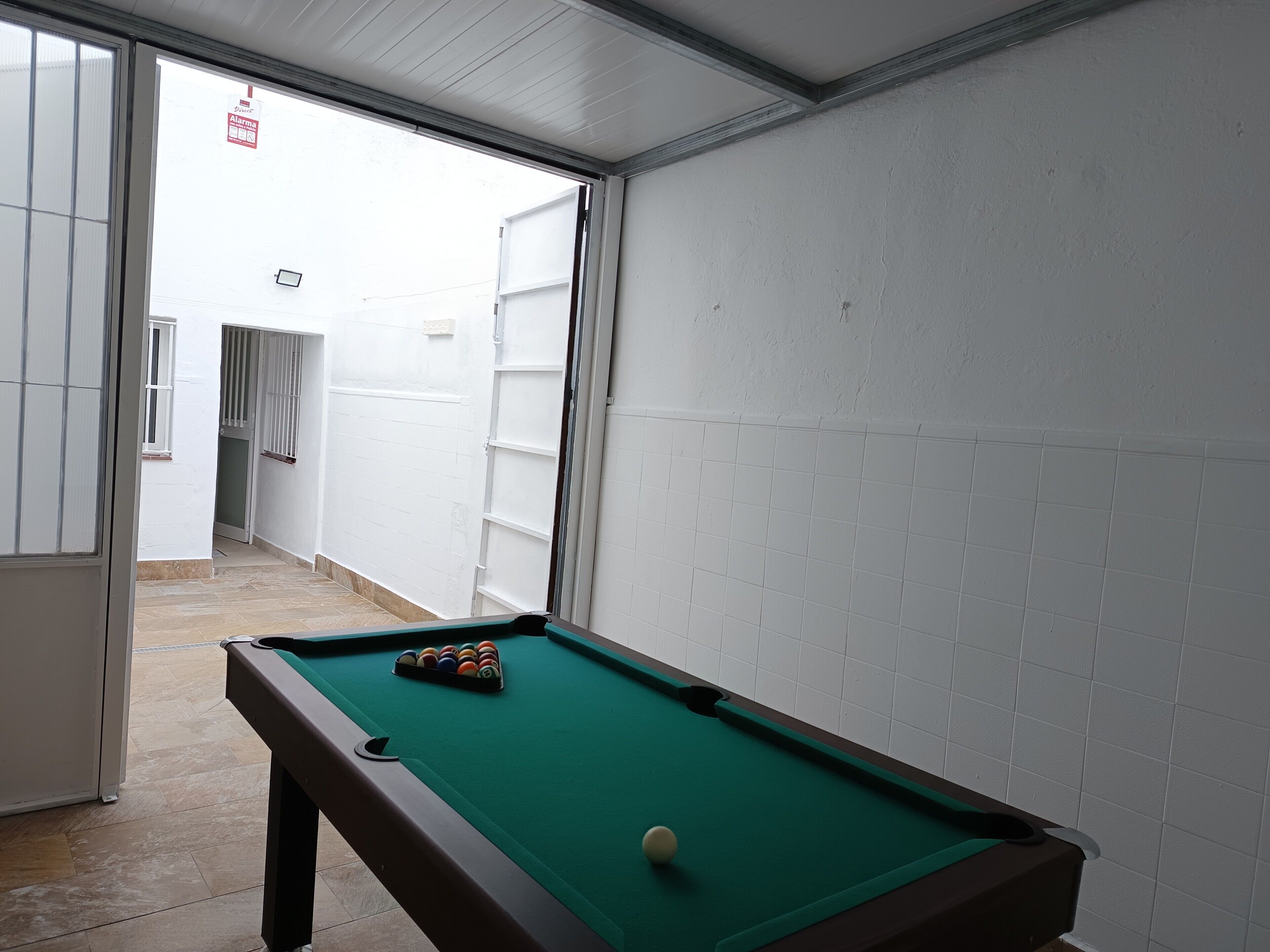 A pool table with balls, a door, and a white tiled wall.