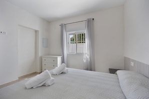 A bedroom with a bed, a bedside table, a dresser, a window with curtains, and a view of greenery outside. - Holiday Home 'Camposoto' with Private Pool, Wi-Fi and Air Conditioning (San Fernando)