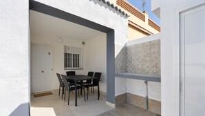 An outdoor patio with a dining table and chairs, a door, and a patterned wall. - Holiday Home 'Camposoto' with Private Pool, Wi-Fi and Air Conditioning (San Fernando)