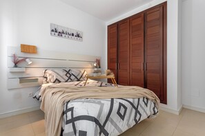 A bedroom with a bed, bedside table, lamp, and a large wardrobe.