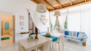 A bright room with a dining table, chairs, a sofa, and a ceiling with wooden beams.