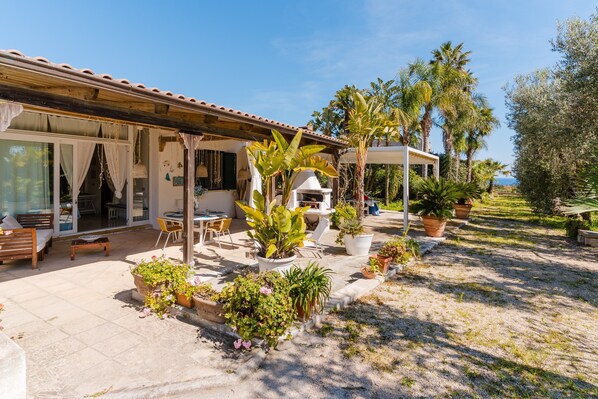 Una casa con patio, mobiliario exterior y plantas en macetas.