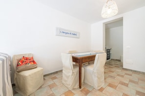 A dining area with a table, chairs, a hanging light fixture, and a wall sign.