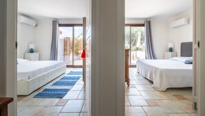 A hotel room with two beds, a large window, and a view of the outside.