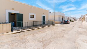 Une rue résidentielle bordée de maisons, avec une chaussée goudronnée et une voiture garée.