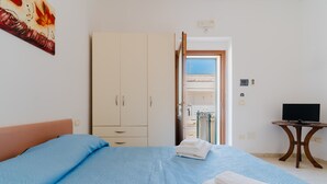Une chambre à coucher avec un lit, une armoire, une télévision et une vue sur l’extérieur.