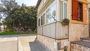 Ein Gebäude mit Steinverkleidung, großen Fenstern und einem Balkon mit Blumen.