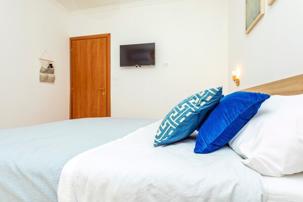 A bedroom with a bed, a television mounted on the wall, and a door.