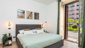 Ein Schlafzimmer mit einem großen Bett, zwei Wandleuchten und einer Schiebeglastür zu einem Außenbereich.