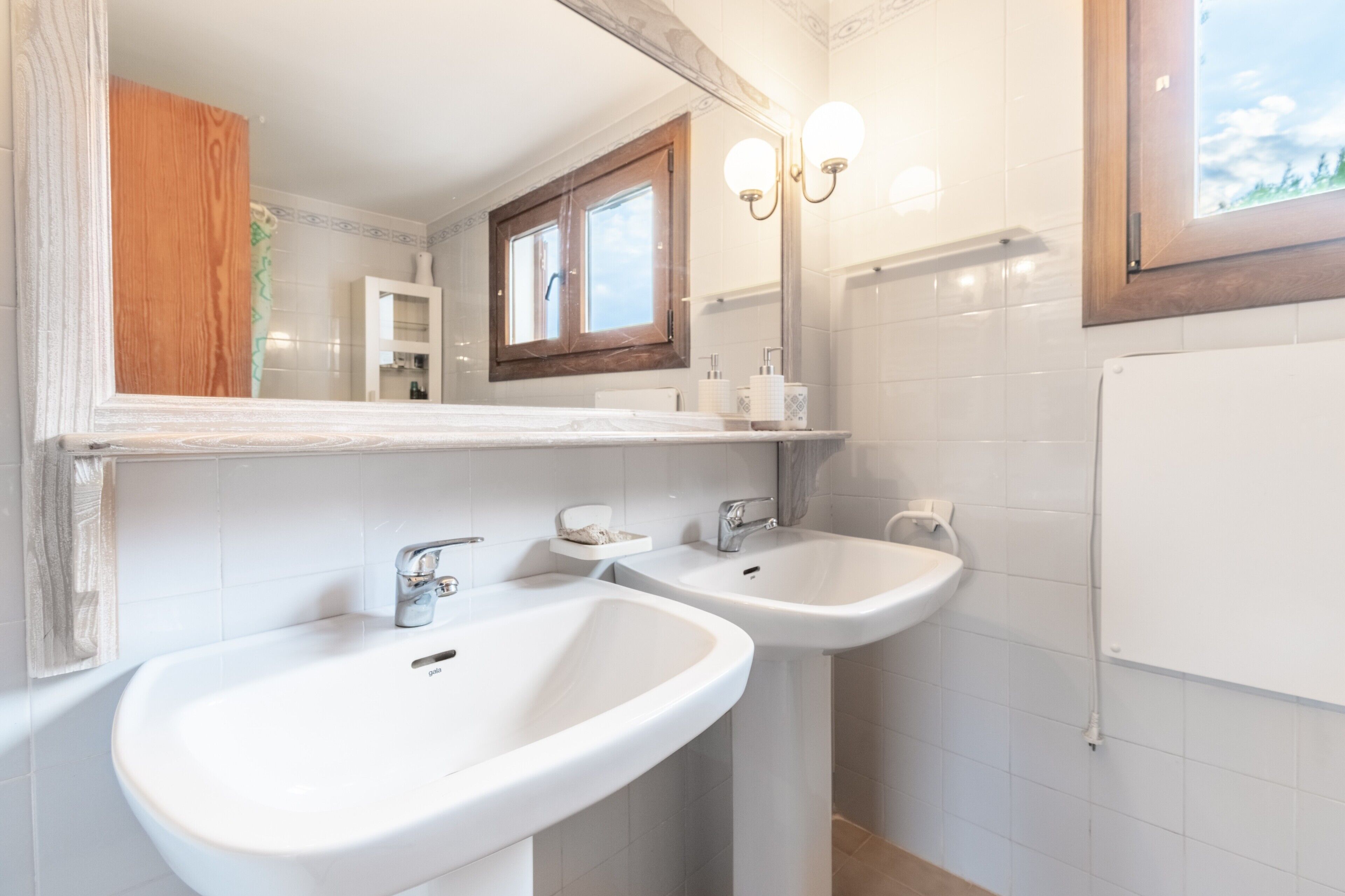 A bathroom with two sinks, a mirror, and a window.