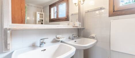 A bathroom with two sinks, a mirror, and a window.