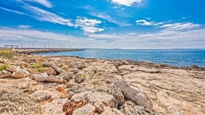 A rocky shoreline with a clear blue sky and calm sea. - Casa Claper: Holiday Home with Shared Pool, Wi-Fi, and Air Conditioning (Unknown)