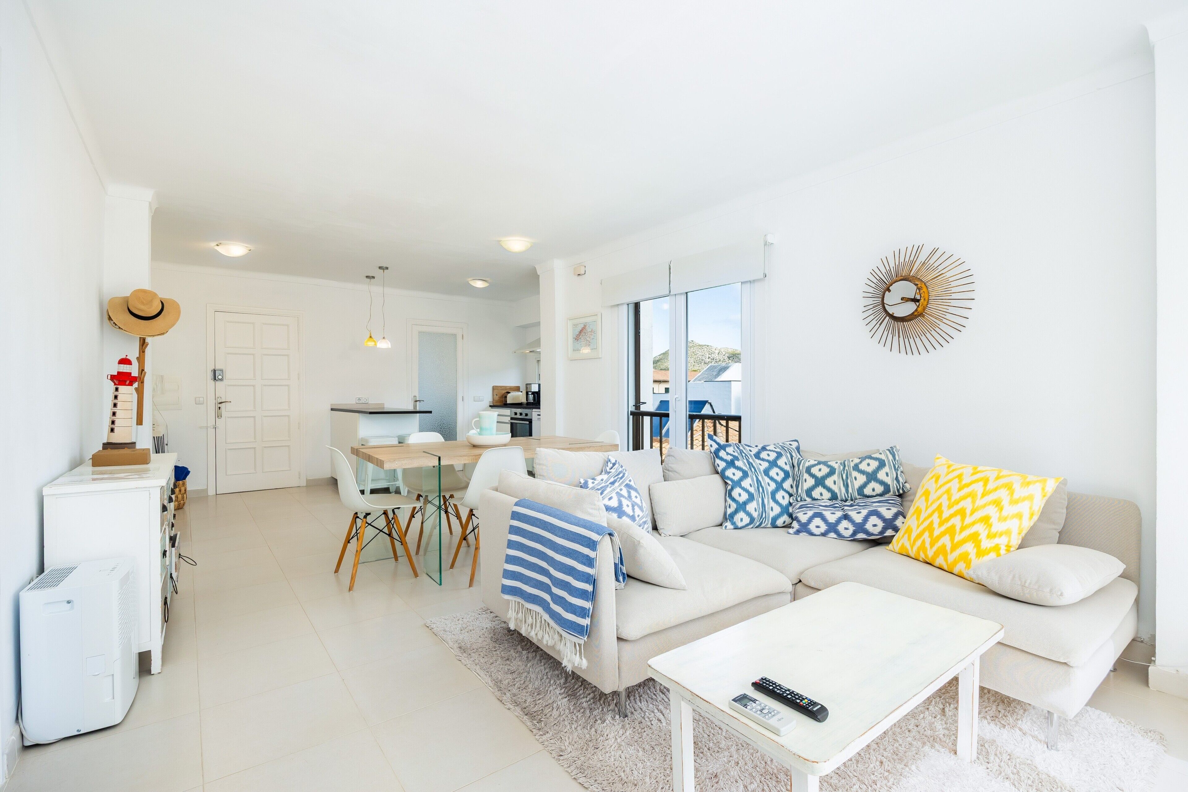 A modern living room with a sofa, coffee table, and a dining area with chairs and a table.