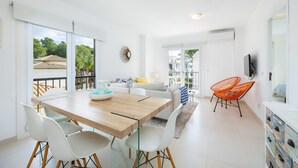 A modern living room with a dining area, large windows, and a balcony. - Apartment Planeta Mallorca in Puerto de Pollensa with Sea Views, Wi-Fi, and Air Conditioning (Unknown)