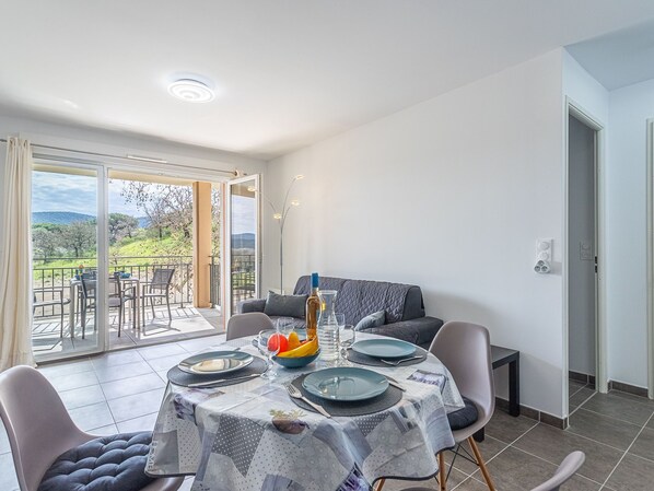 A dining area with a table set for four, a sofa, and a view of the outdoors. - Eden Golfe by Interhome (Cogolin)