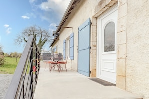 A building with a patio area, a table with chairs, and a door. - Gîte du Cerisier – Authentic Holiday Home in the Heart of Périgord Vert (Lanouaille)