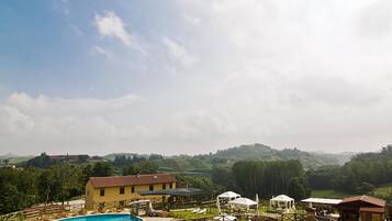 A pool area with lounge chairs, a building, and a hilly landscape in the background.