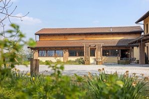 A two-story building with a tiled roof, large windows, and a gravel driveway.
