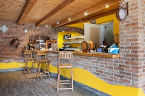 Un espace bar avec des tabourets en bois, un mur en briques et un mur d’accent jaune.