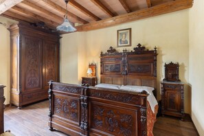 Un dormitorio con cama de madera, un armario grande y un ventilador de techo.