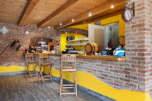 Un'area bar con sgabelli di legno, un muro in mattoni e una parete gialla.