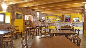 En restaurant med træborde og stole, murstensvægge og en gul accentvæg.