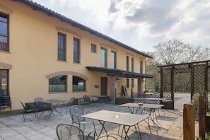 A building with outdoor seating, a pergola, and a view of trees.