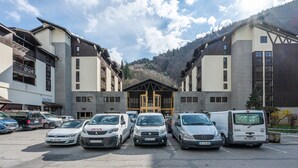 A parking lot with several cars and a building with a central entrance.