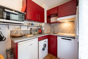 Una cocina compacta equipada con microondas, tostadora, pileta y lavavajillas.