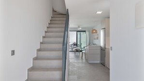 Um interior moderno com uma escada que leva a uma sala de jantar e cozinha.