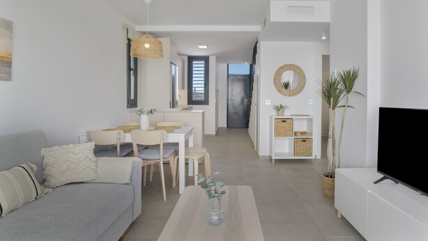 Uma sala de estar moderna com sofá, mesa de centro, TV, espaço de refeições e cozinha.