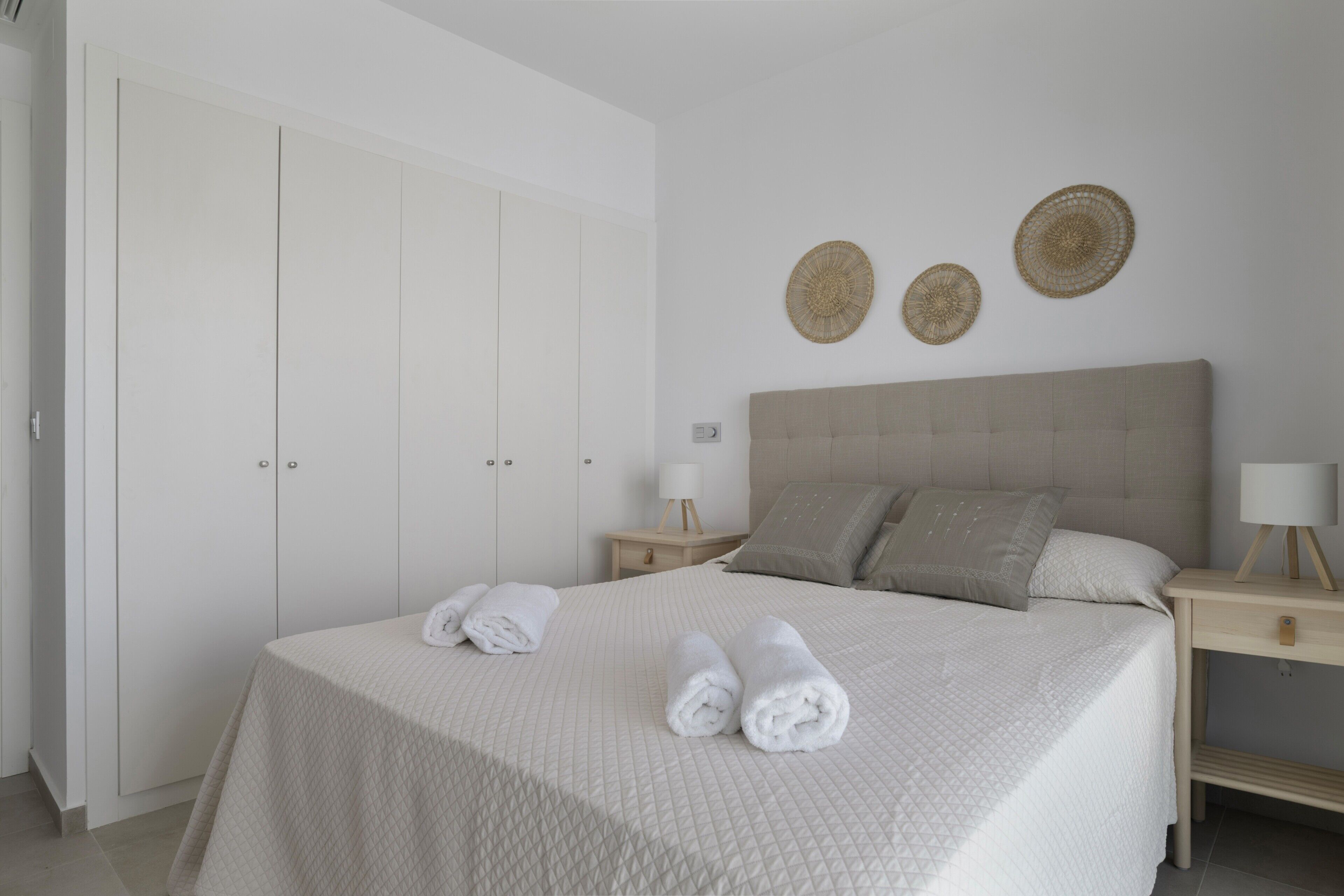 Une chambre à coucher comprenant un lit, deux tables de chevet, une armoire et des éléments décoratifs muraux.