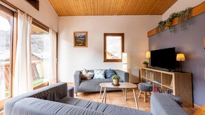 A living room with a grey sofa, a coffee table, a TV, and a bookshelf.