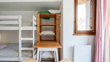 Een slaapkamer met een stapelbed, een houten bureau en een radiator.