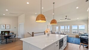 Una cocina amplia con una isla grande, iluminación colgante y vistas al área de estar.