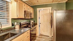Una cocina con armarios de madera, un refrigerador de acero inoxidable, un microondas y una estufa.