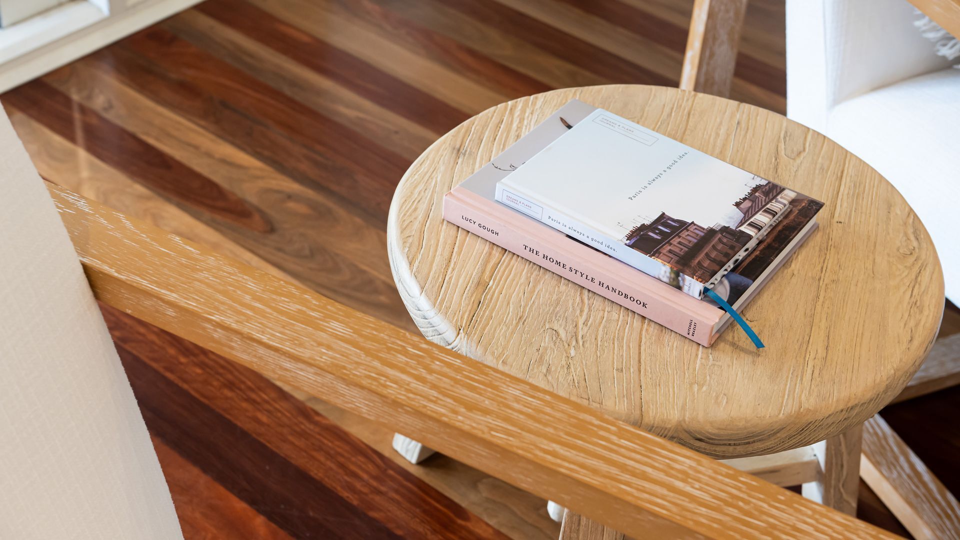 Un tabouret rond en bois, sur lequel repose un livre intitulé « Le guide pratique du style intérieur », de Lucy Gough, ainsi qu’un autre livre.