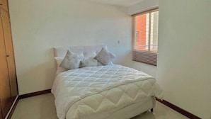 Una camera da letto con un letto, un armadio in legno e una finestra con persiane.