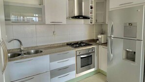Una cucina moderna con elettrodomestici in acciaio inossidabile, mobili bianchi e un piano di lavoro in granito.